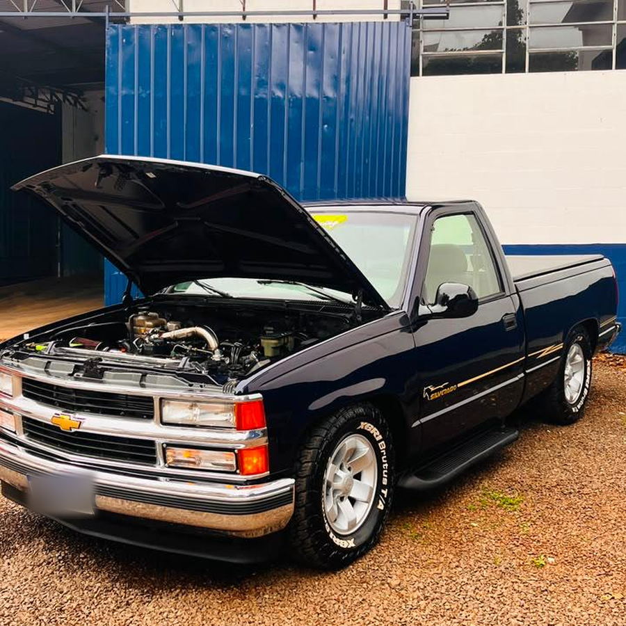 Chevrolet Silverado azul-escuro com o capô aberto na área externa da Mecânica ProAuto